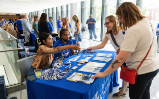 Students shaking hands with people tabling an event