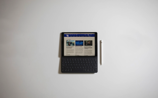 A zoomed out view of an ipad with an apple pencil next to it.