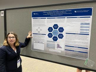 a woman standing in front of a research poster gesturing towards it and talking