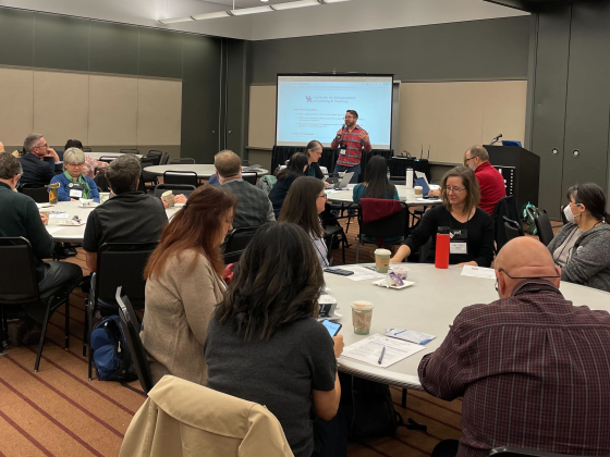 celt staff trey conatser speaking in front of several round tables of POD Network conference participants